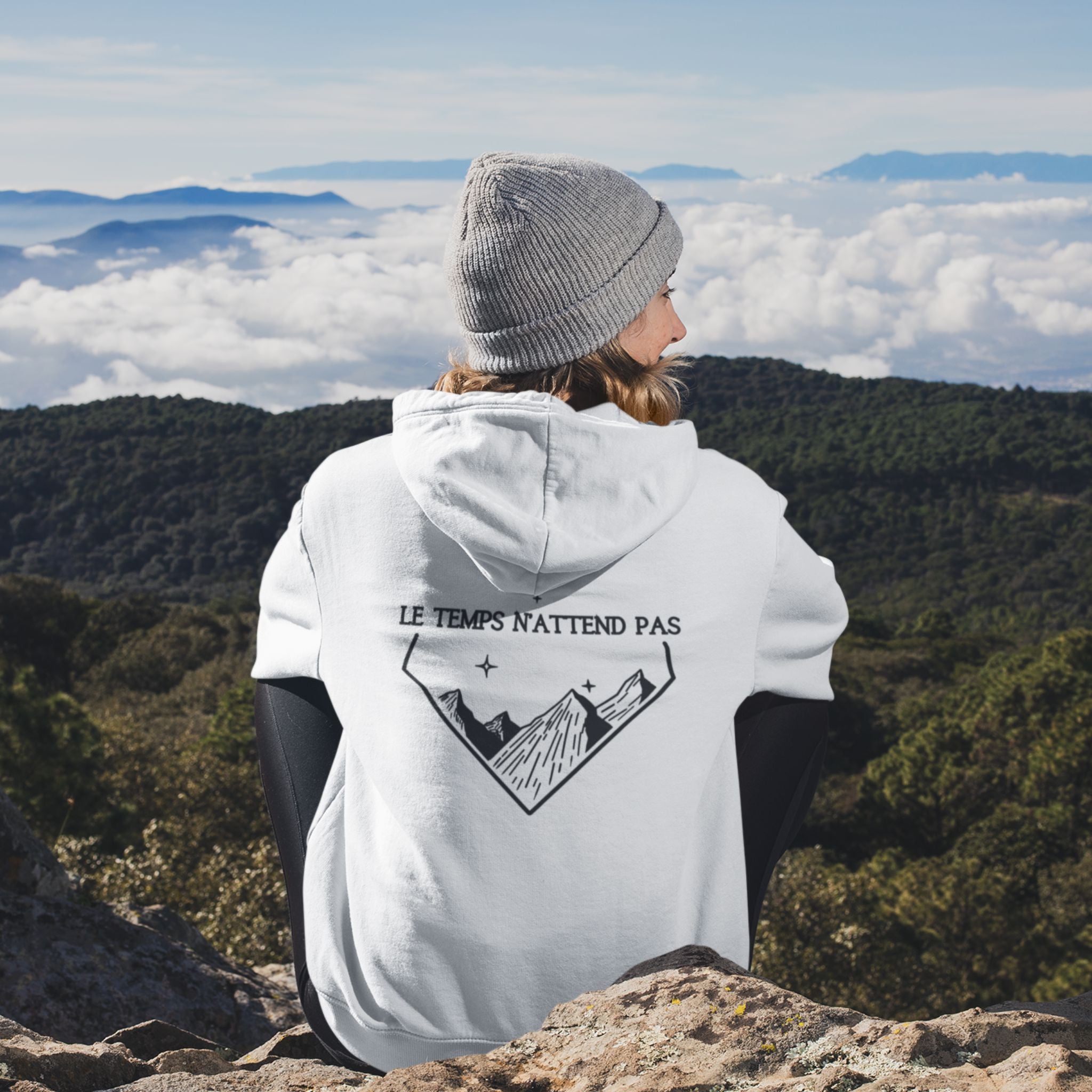 veste à capuche non genrée blanche avec fermeture éclair, le logo flame and spirit brodé sur la poitrine gauche et un design montagne au dos et une affirmation positive le temps n'attend pas.