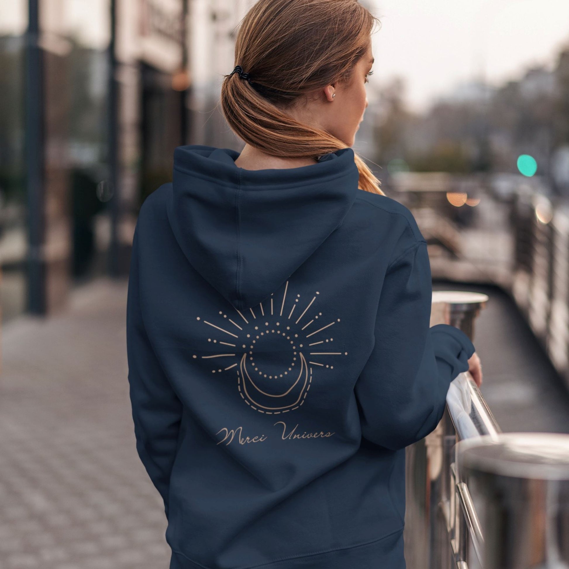 Veste à capuche non genré, bleu marine avec message dans le dos Merci Univers et symbole graphique lune et soleil. Logo brodé Flame and Spirit poitrine gauche.