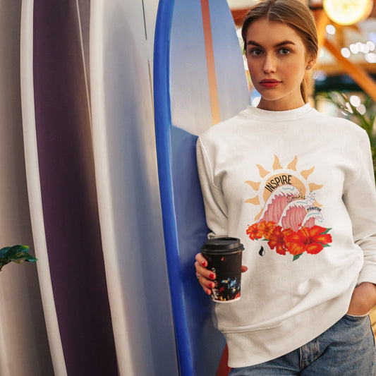 Sweat-shirt unisexe, avec texte de développement personnel sur la partie ventrale, inspire, souris, positive, associés aux symboles des vagues, du soleil et des hibiscus, fond blanc. Logo brodé Flame and Spirit sous la nuque.