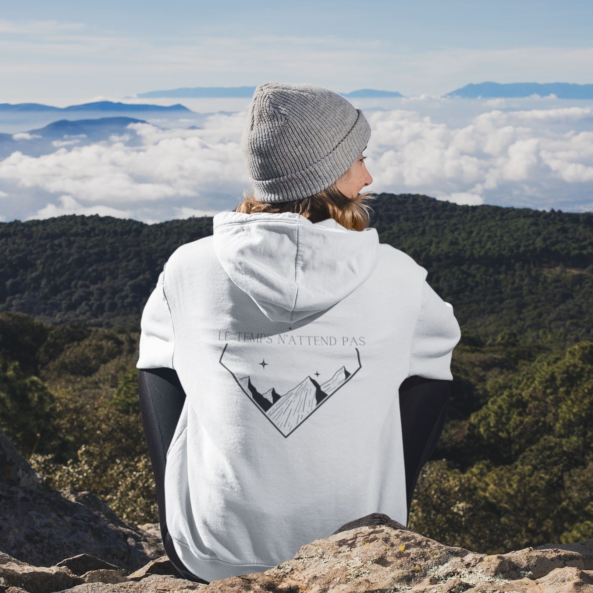 veste à capuche unisexe blanche avec fermeture éclair, le logo flame and spirit brodé sur la poitrine gauche et un design montagne au dos et une affirmation positive le temps n'attend pas