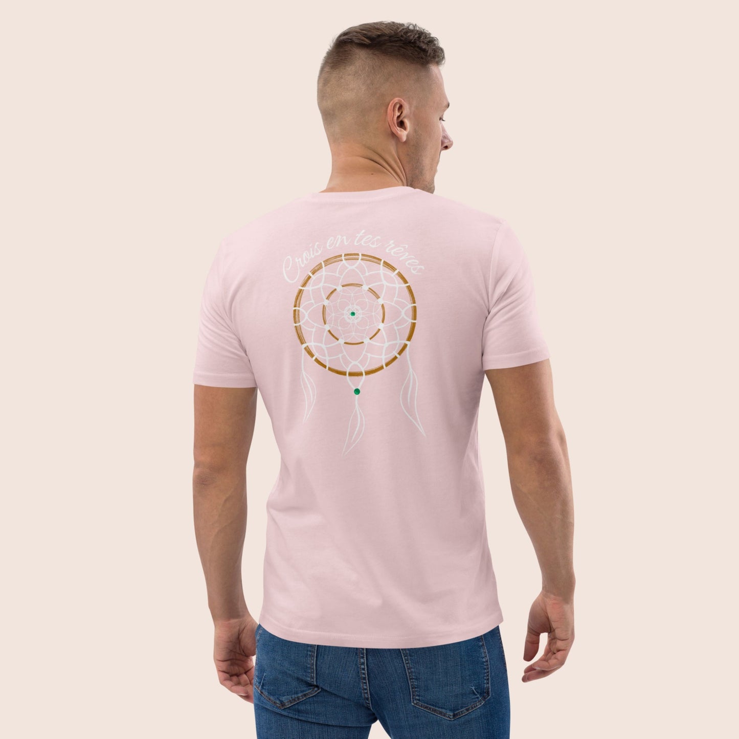 T-shirt non genré, avec affirmation positive dans le dos Crois en tes rêves et symbolique graphique de l'attrape rêve sur fond rose pale. Logo brodé Flame and Spirit poitrine gauche.