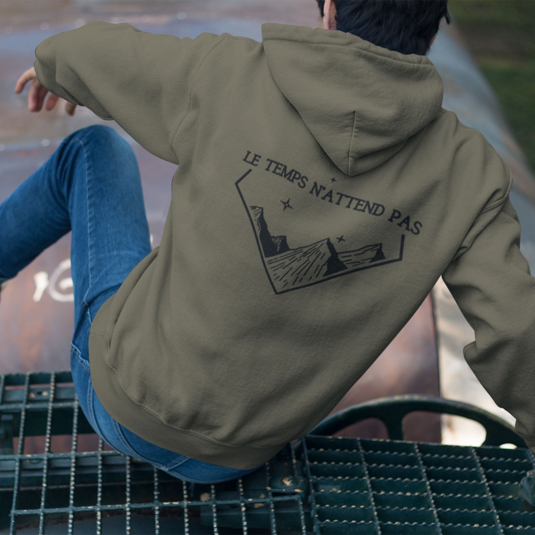 Sweat à capuche non genré avec phrase d'inspiration dans le dos Le temps n'attend pas et symbole de montagnes graphique noir sur fond kaki. Logo brodé Flame and Spirit poitrine gauche. Zoom sur le message motivant et l'alignement avec tes ambitions.