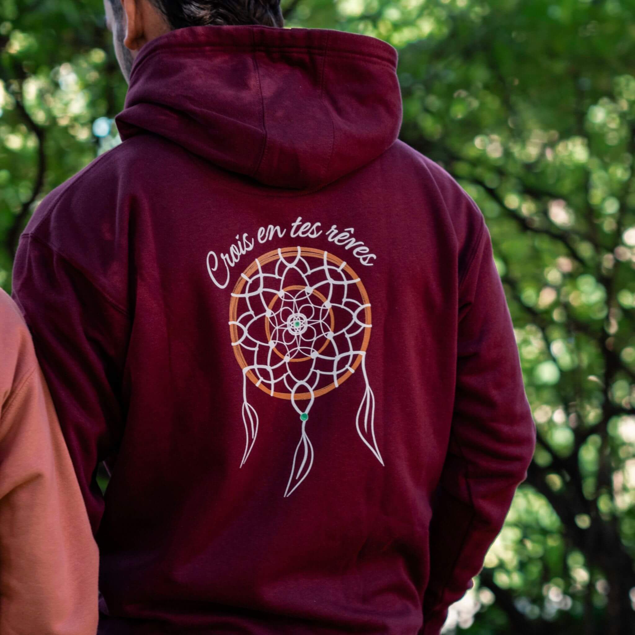 Sweat à capuche bordeaux Flame & Spirit avec motif attrape-rêve et message "Crois en tes rêves", photographié en extérieur.