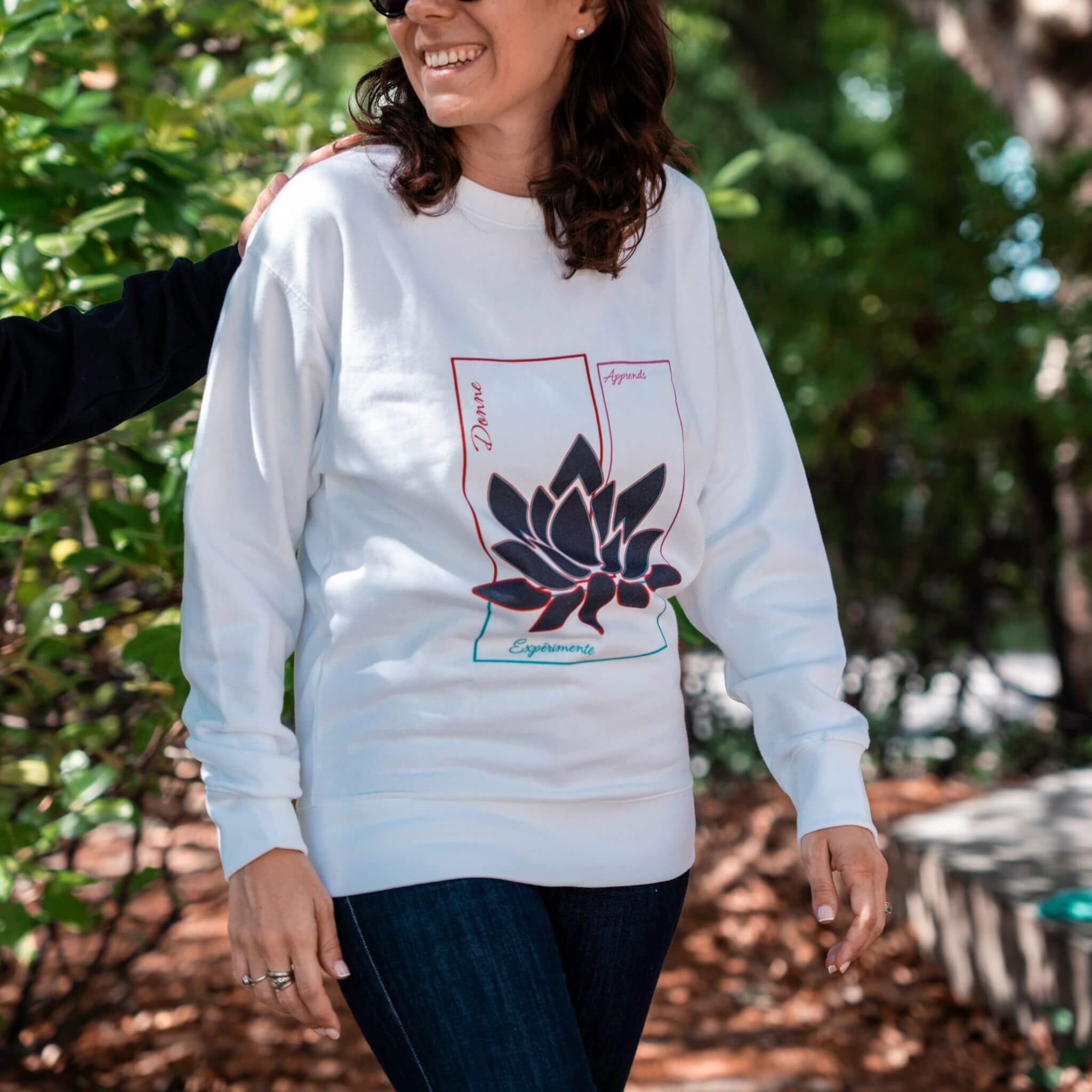Sweat blanc Flame & Spirit avec motif lotus et message inspirant, porté en extérieur.